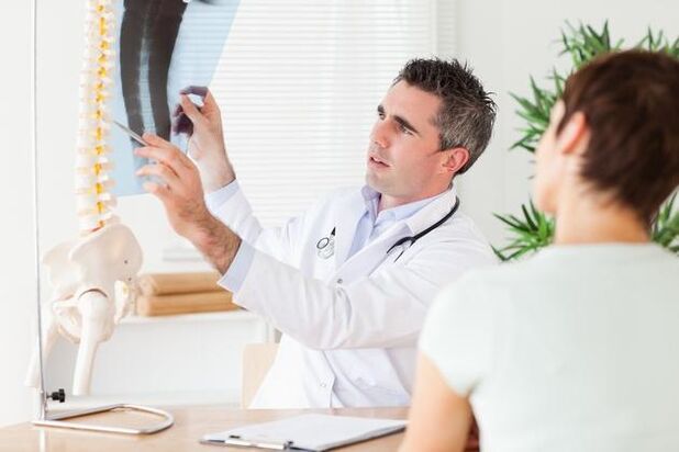 o médico mostra o dano na columna vertebral debido á osteocondrose cervical